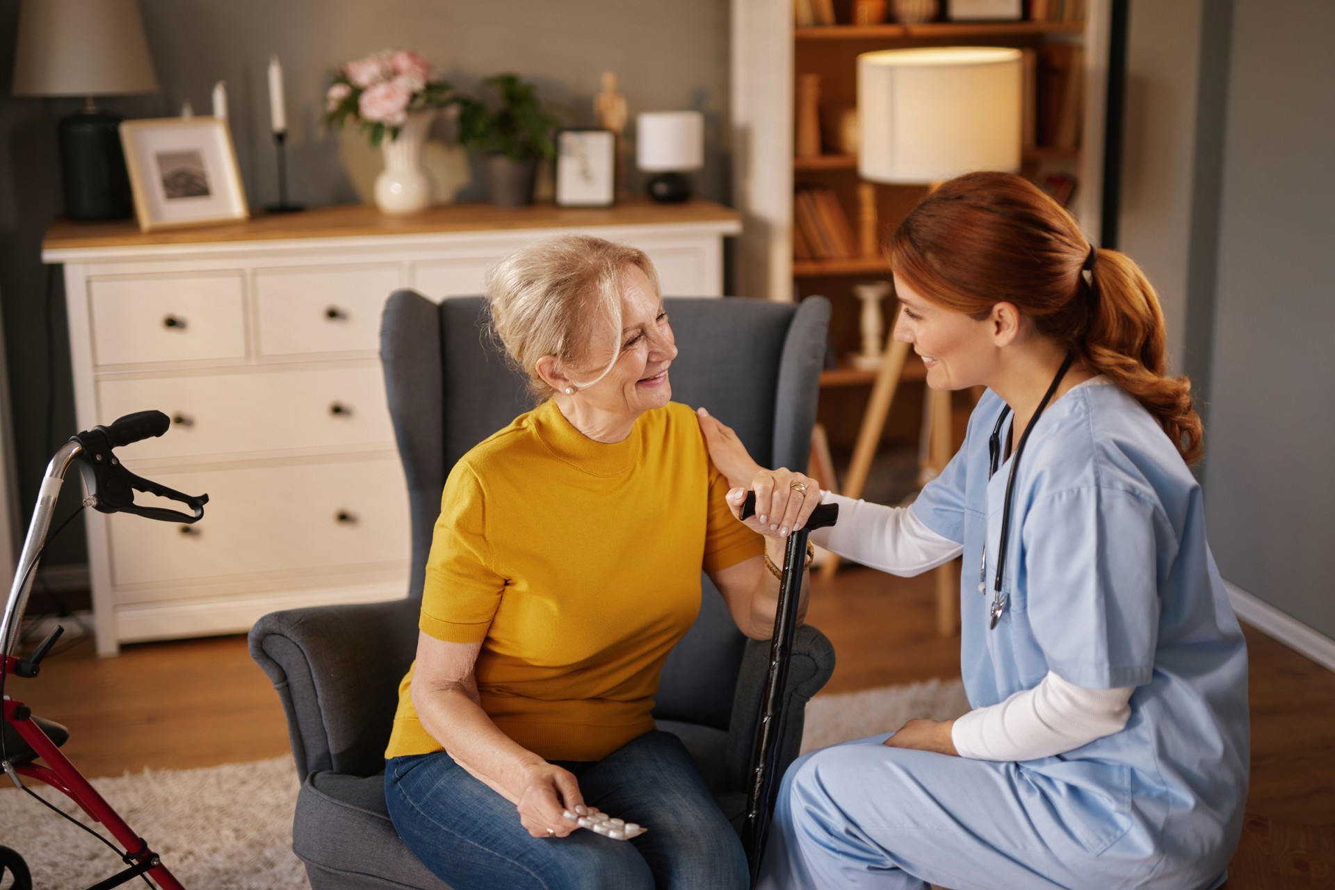 Nurse assisting elderly woman with walking cane at home